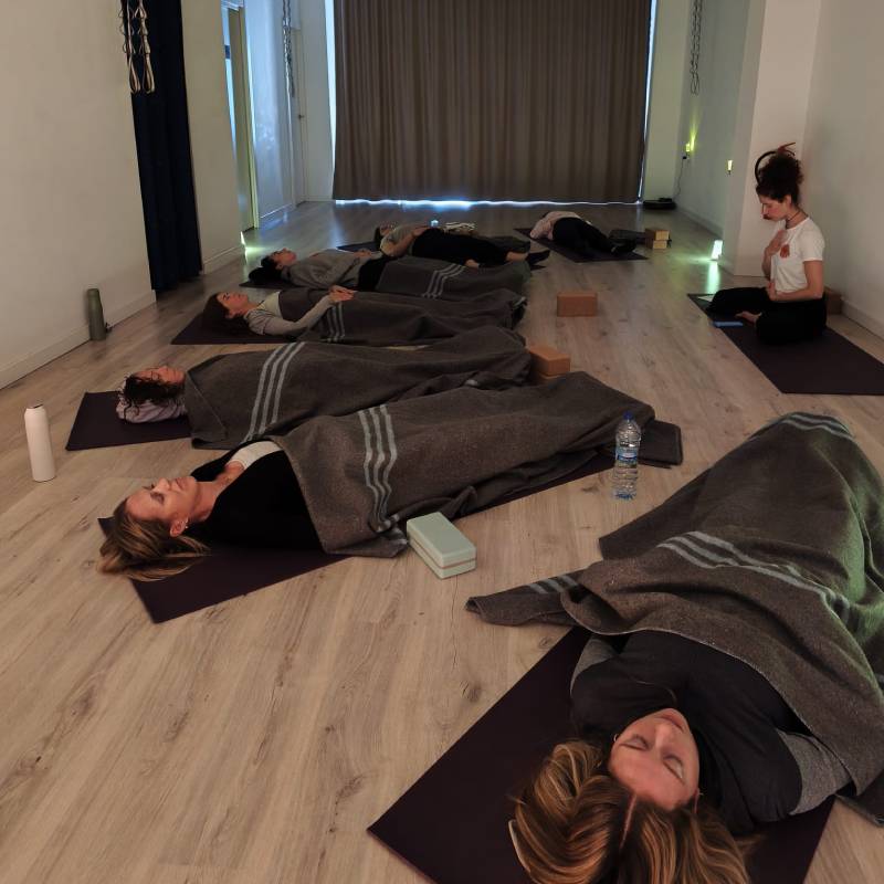 Grupo de mujeres en relajación final (savasana) durante una clase de yoga femenino